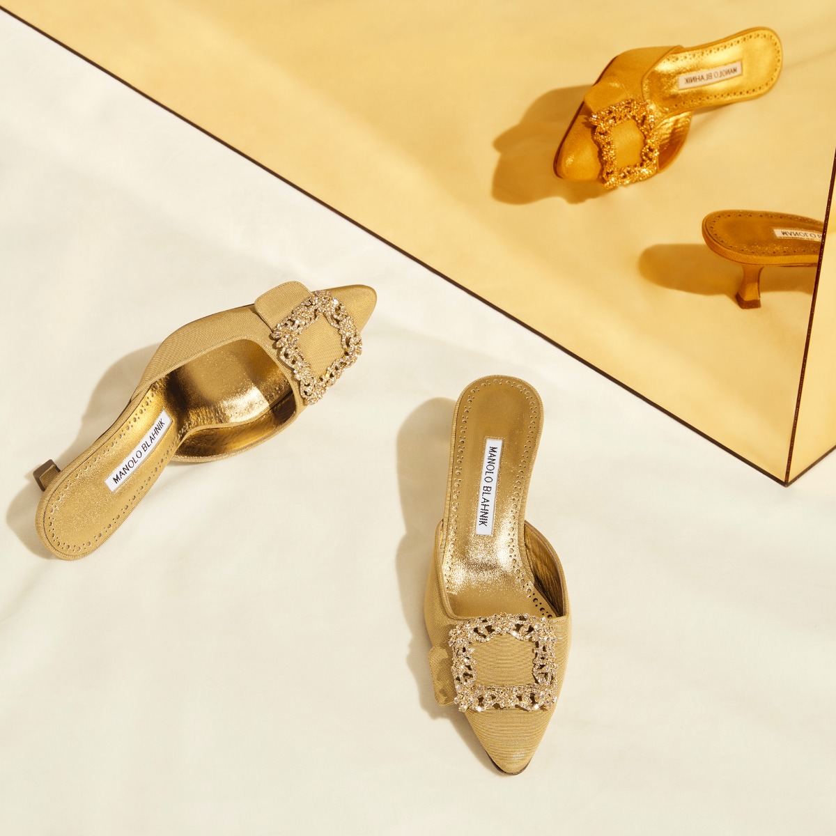 Editorial image of the gold edition Maysale mules, reflected in a mirrored gold box.