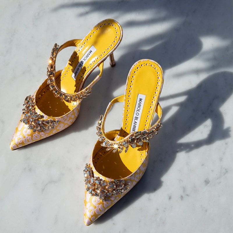 Editorial image of the yellow jacquard mule, Lurum, against a marble background.