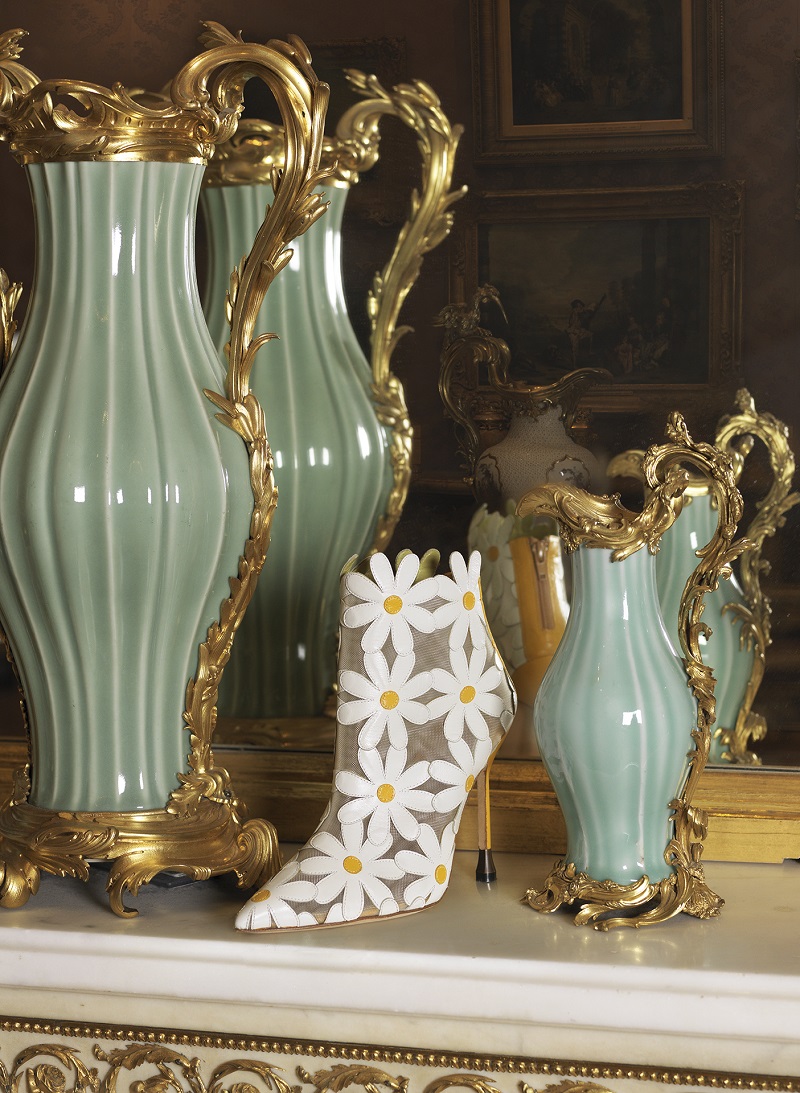 A white Manolo Blahnik boot on a marble bench top.
