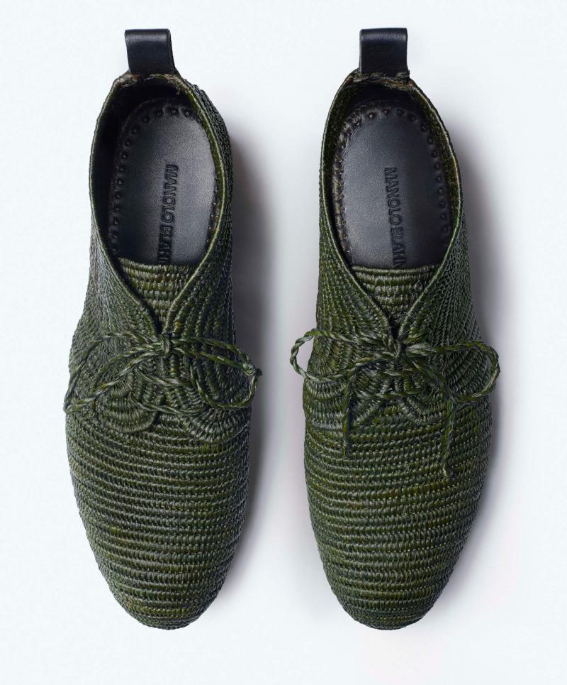A pair of men’s green angle boots made from hand woven raffia. The shoes are in parallel and are on a white background. 