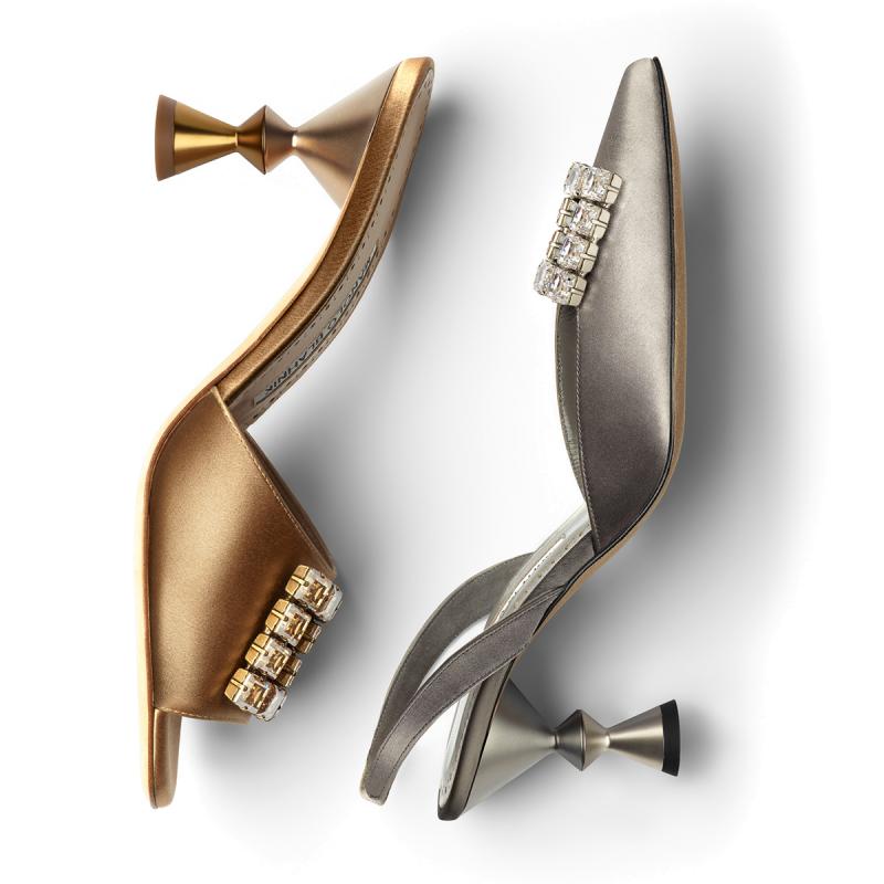 A gold shoe on the left and a silver shoe on the right, both have a sculptural heel. Both shoes have jewelled embellishments