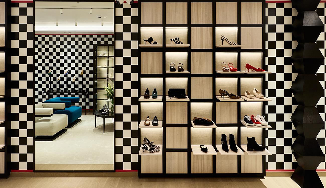 Image of the inside of the Milan store, showing a shoe shelf against a black and white chequered wall. 