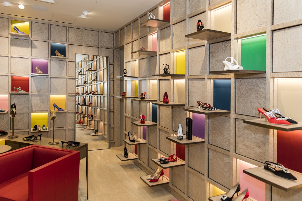 A corner view, inside the Selfridges store. The walls are in a grid with shoes positioned in each square of the grid. 