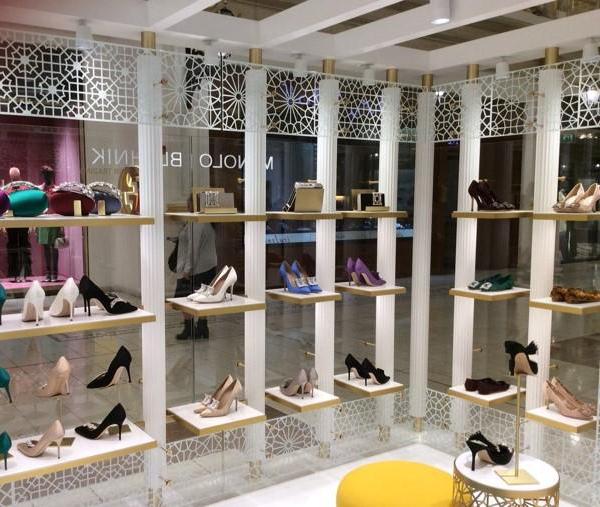Inside the Doha store. There are eighteen white rectangular shelves with shoes on. 