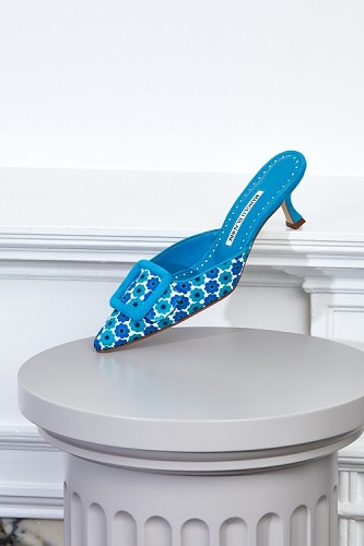 A blue floral printed mule displayed on a plinth