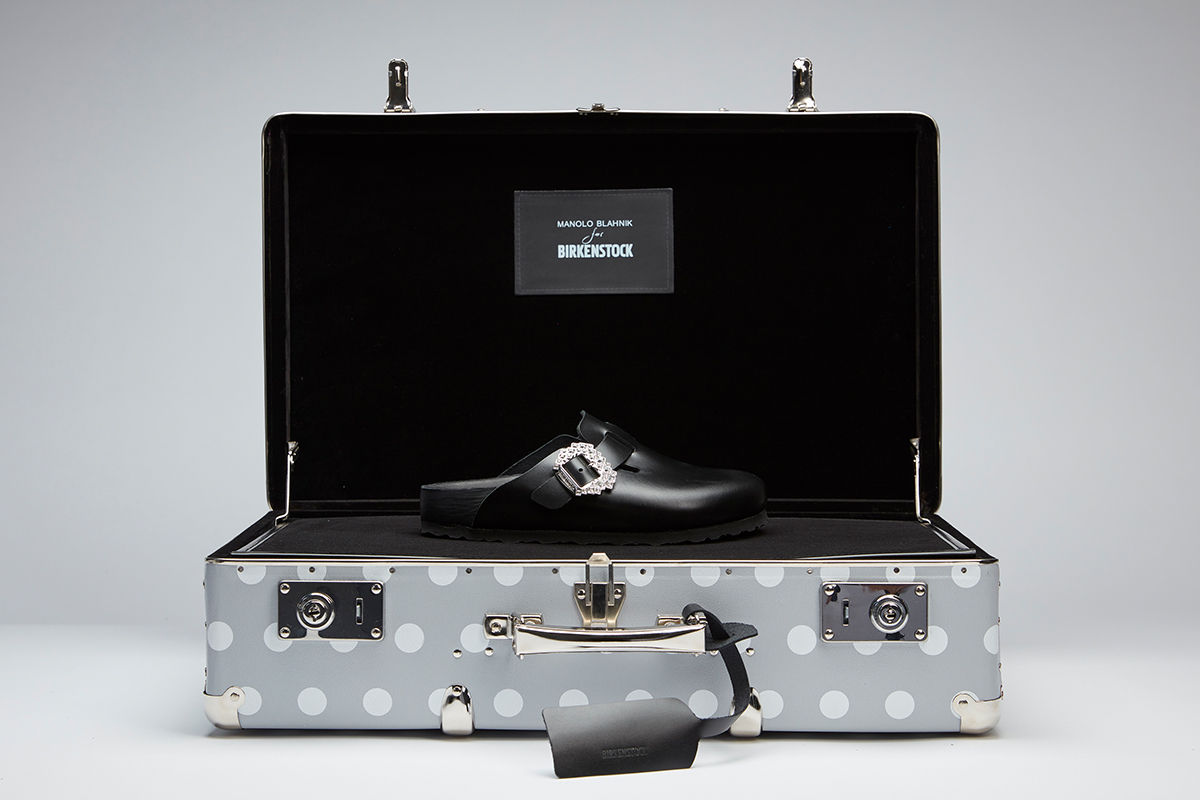 Editorial image of the black calf leather Boston clog in a branded grey and white polka dot suitcase.