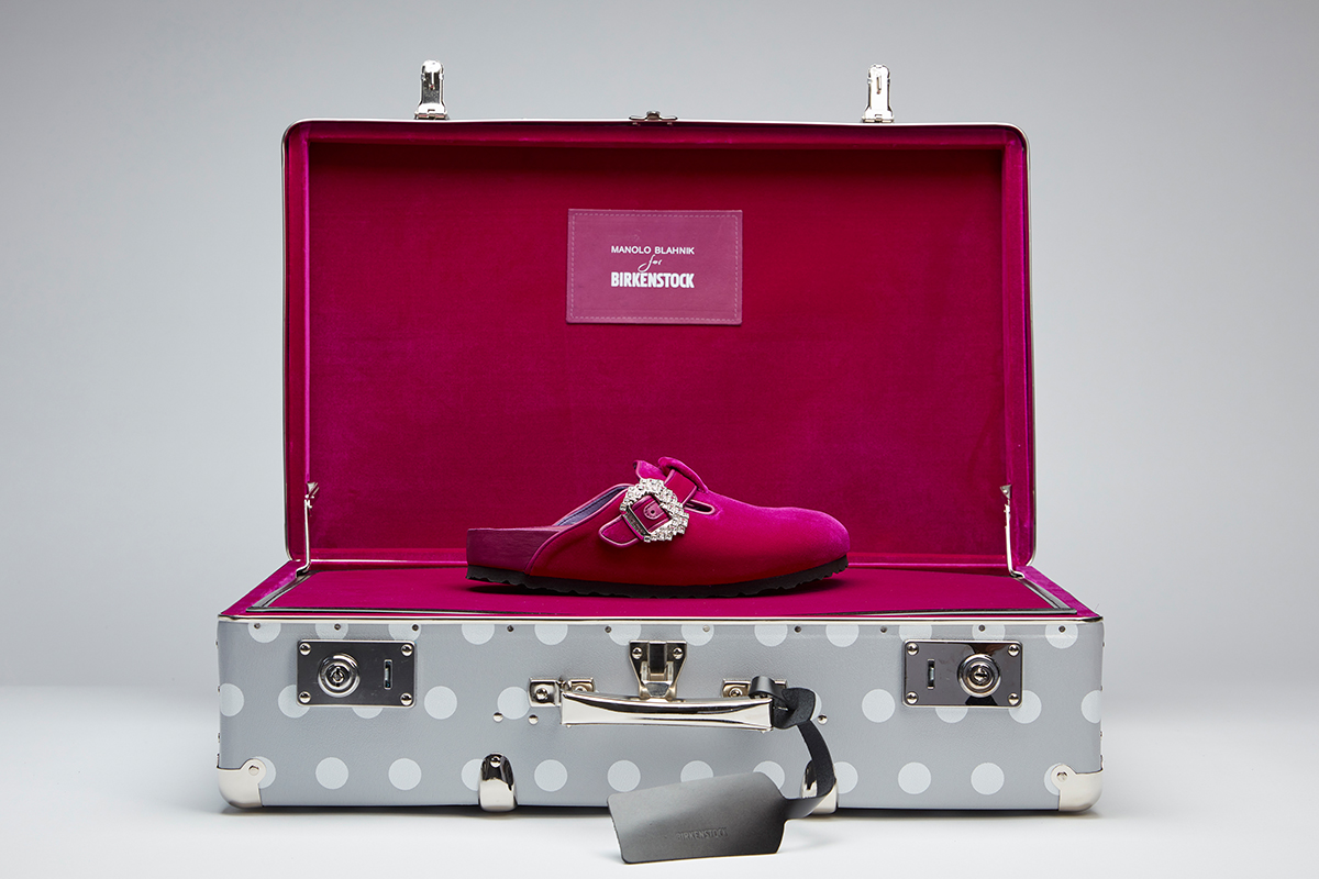 Editorial image of the fuchsia velvet Boston clogs in a branded grey and white polka dot suitcase.