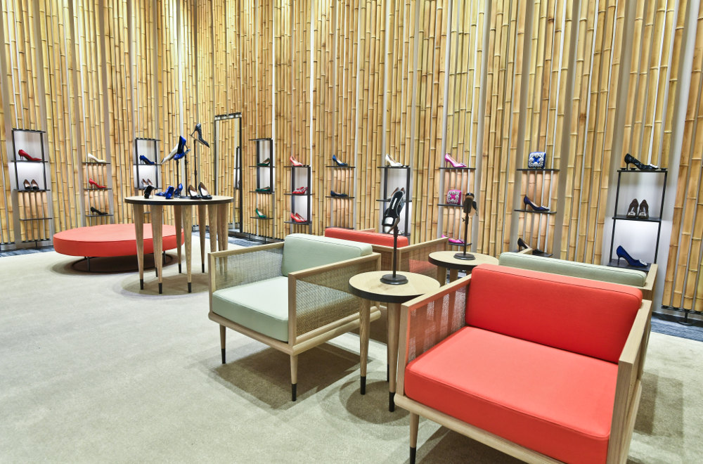 An internal view of the Breeze NanShan store. There are arm chairs. There are shoes on circular tables, and the walls. 