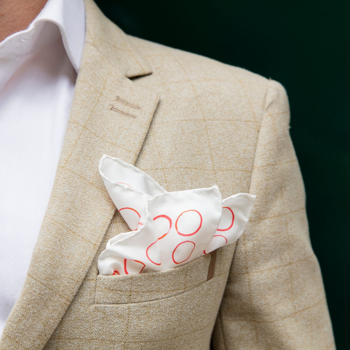 The red and white ‘circles’ pocket square being worn in the top breast pocket of a man’s suit. 