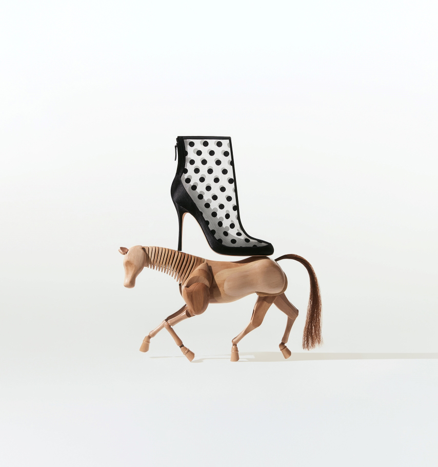 Black polka dot mesh ankle boot on top of wooden horse.  