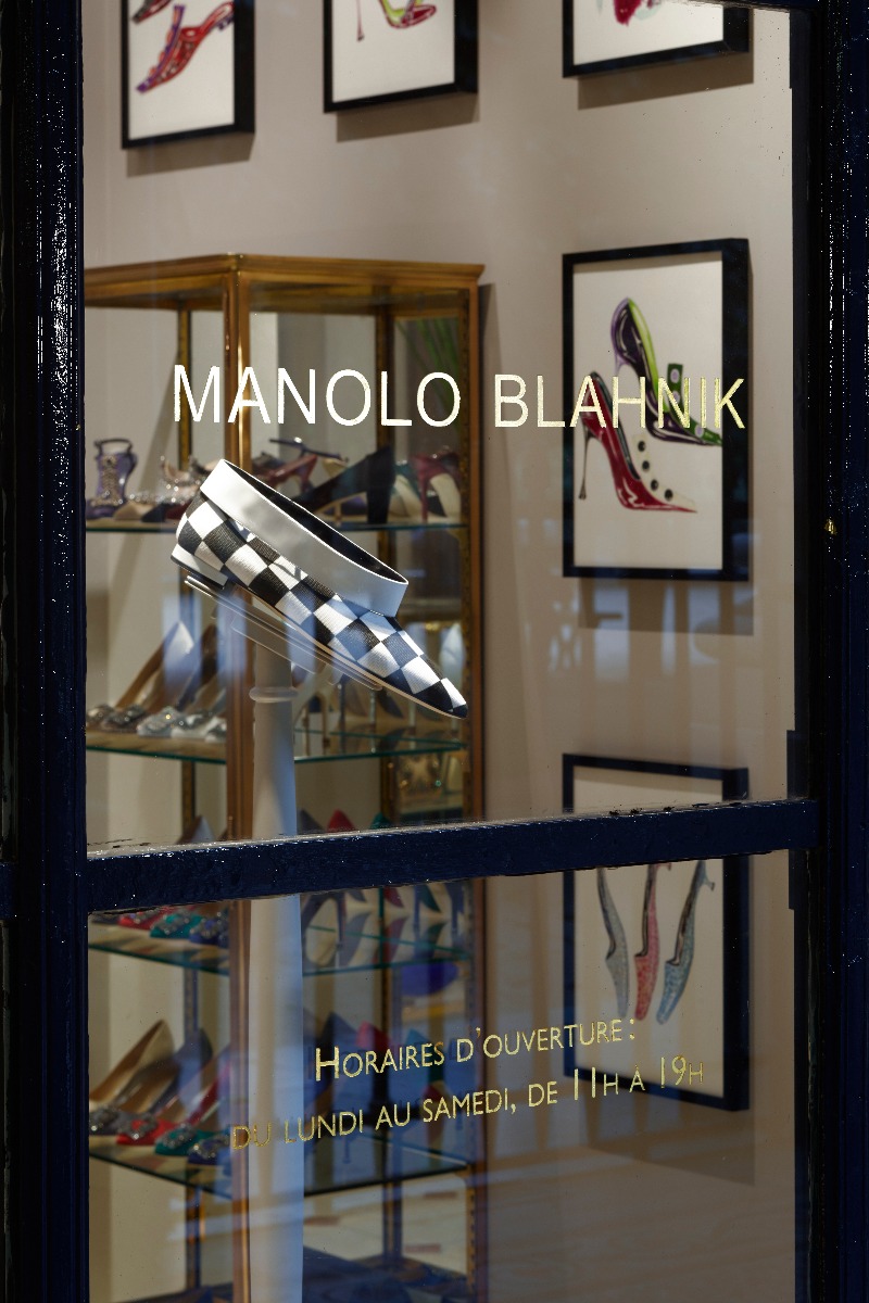 The window of the new Paris store. A black and white check shoe can be seen through the window. 
