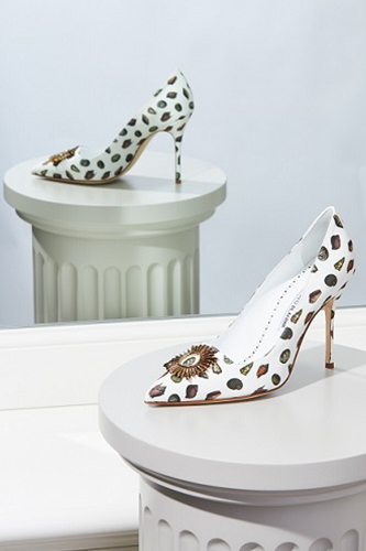 A white linen shoe with a shell print displayed in front of a mirror